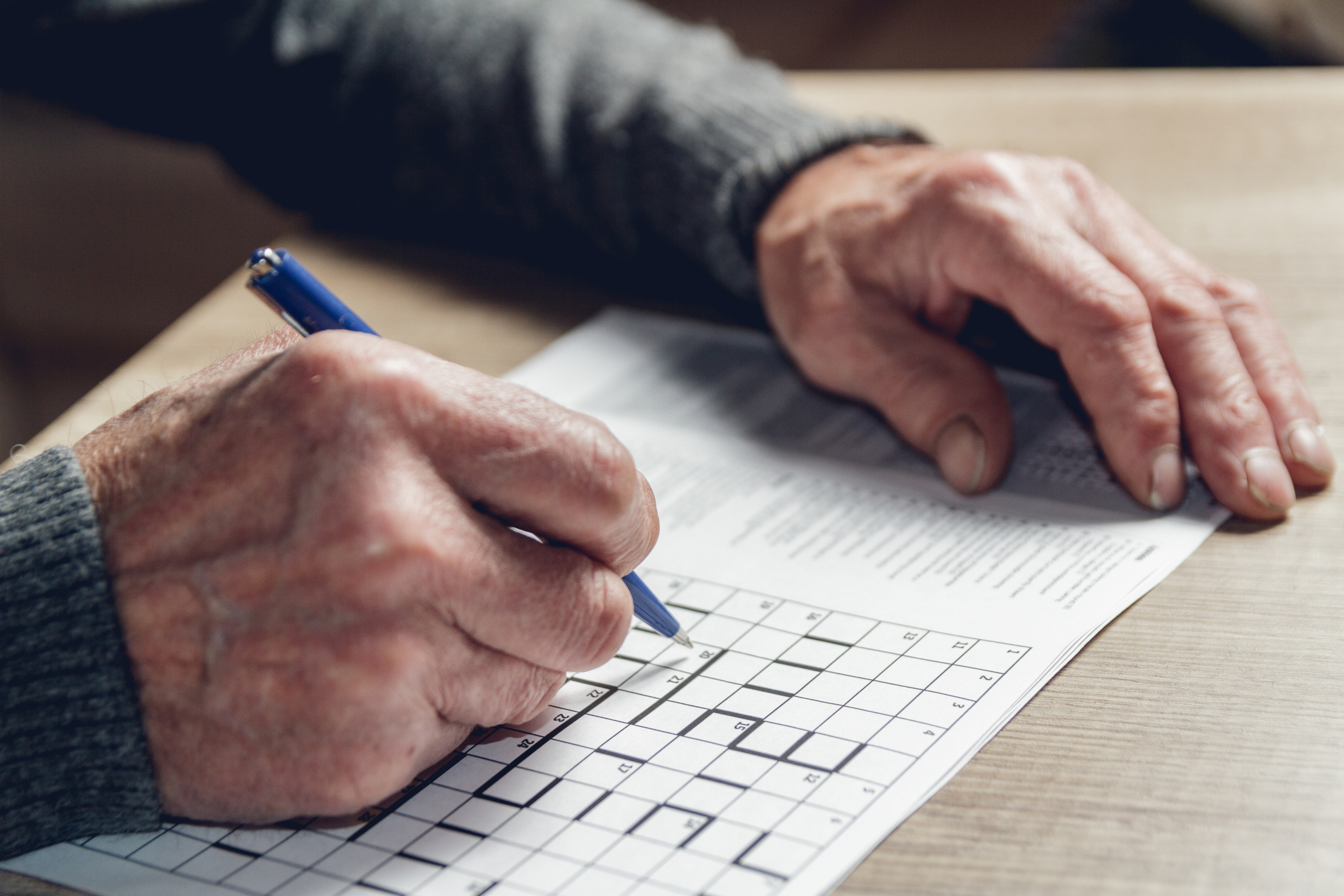 Senior male hands doing a crossword puzzle